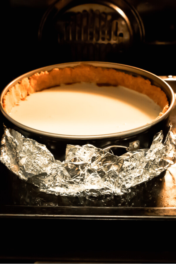 water bath springform pan holding a Bailey's Irish Cream Cheesecake in the oven