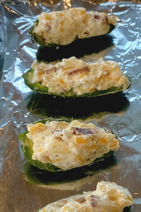 stuffed jalapeno poppers on a baking sheet lined with foil