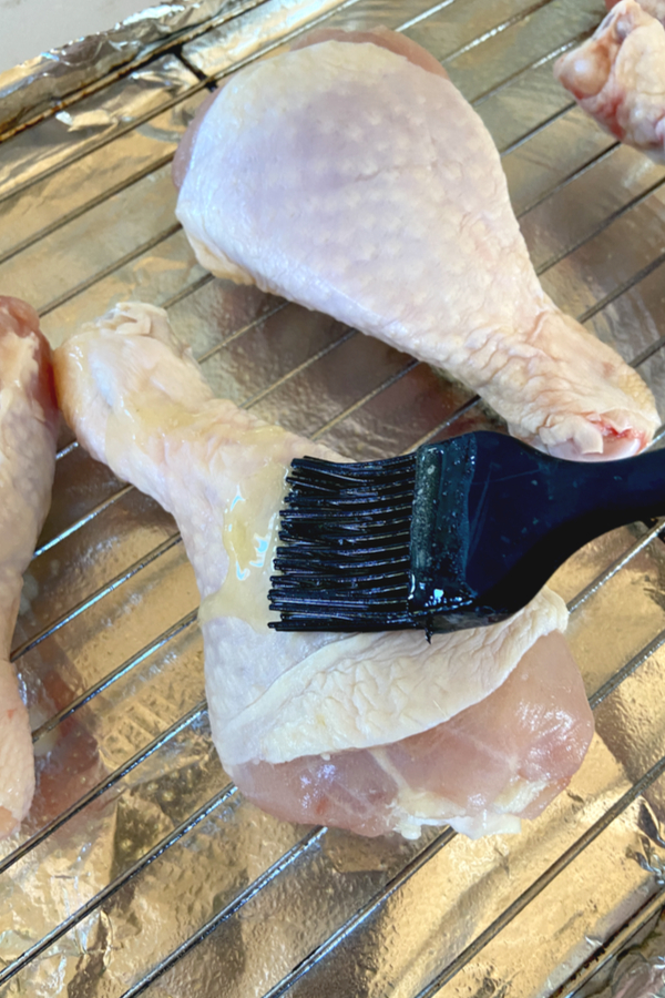 brushing melted butter on chicken legs