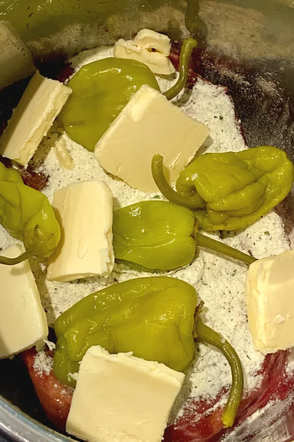 pepperoncini peppers and pads of butter in slow cooker 