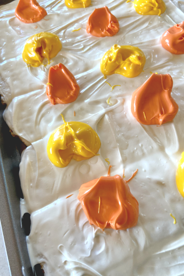 yellow and orange dollops of melted chocolate over white candy