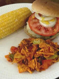 Doritos taco salad with a hamburger and corn on the cob