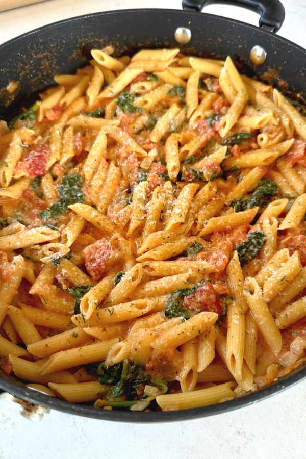 creamy tomato spinach pasta in skillet 