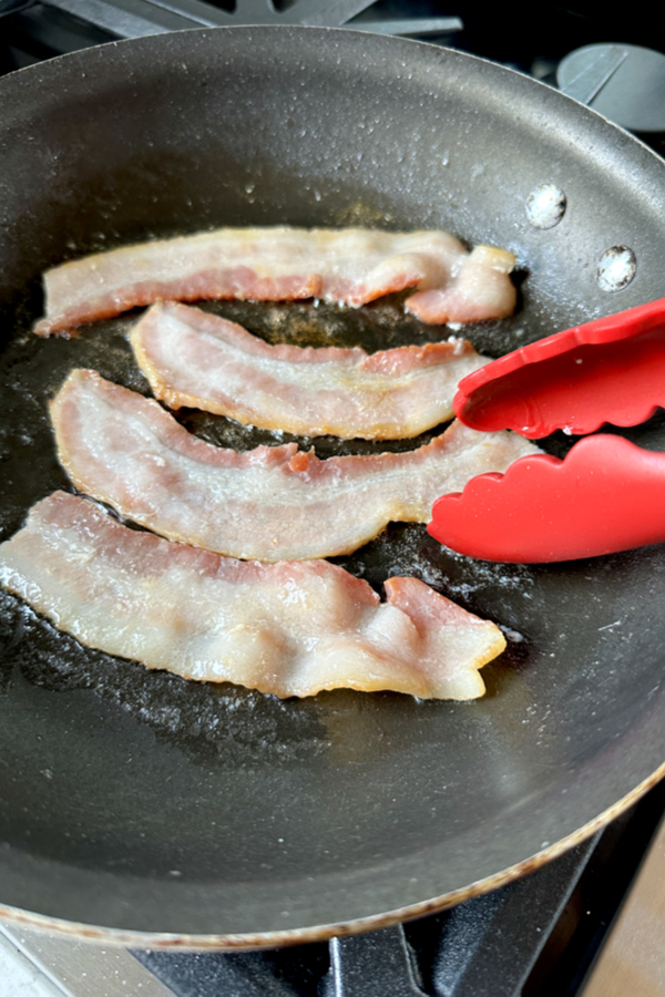cooking bacon strips in skillet 