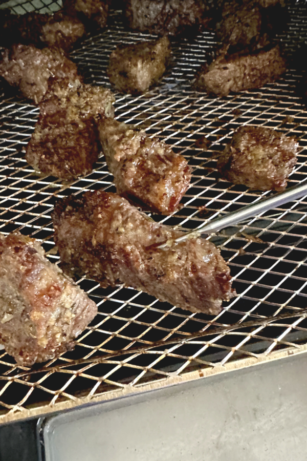 thermometer inserted in steak bites cooked in an air fryer