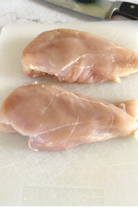 two chicken breasts on cutting board