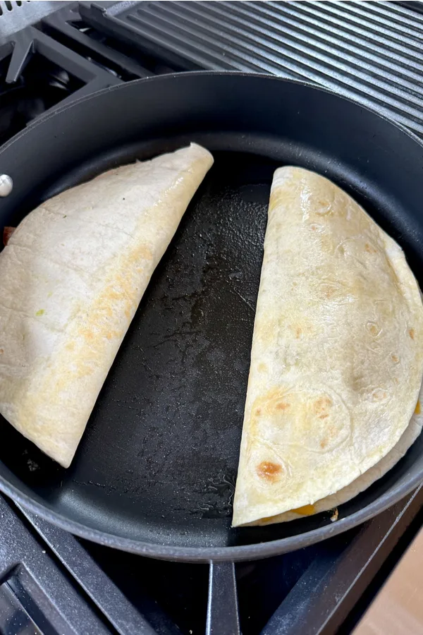 two folded quesadillas in skillet 