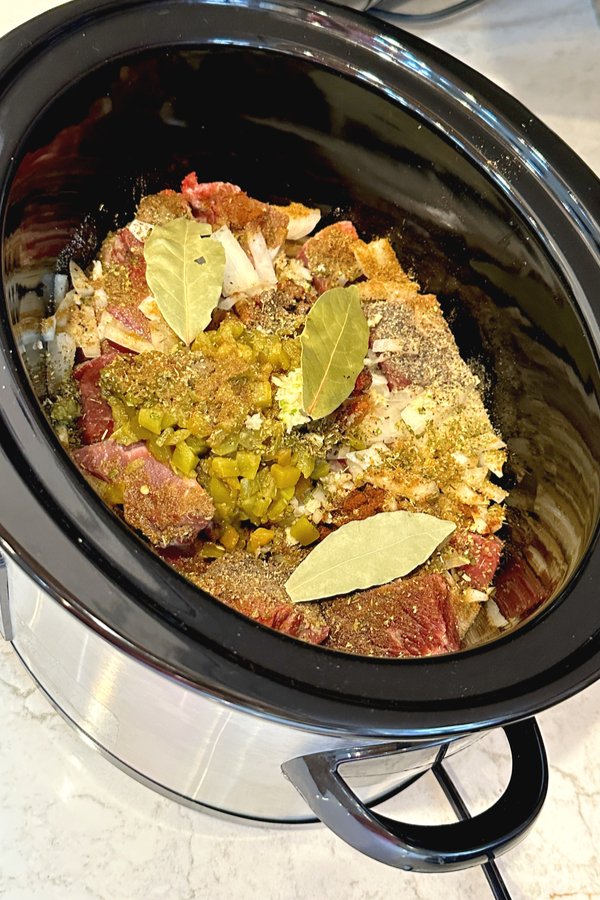 chuck roast topped with barbacoa ingredients in crock pot