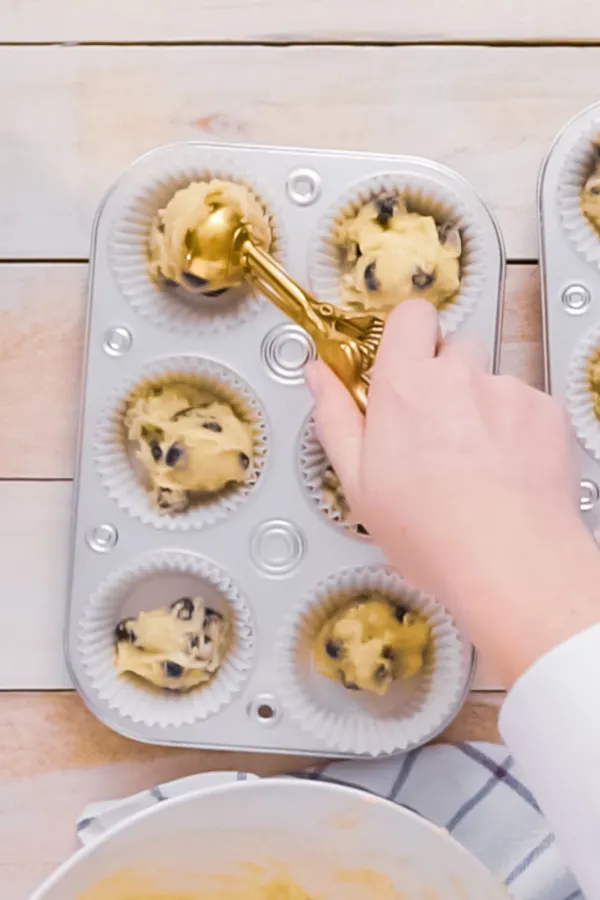 using a cookie scoop to fill muffin tin