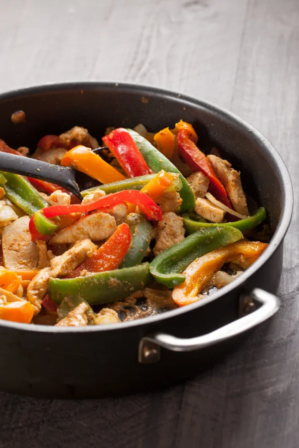 cooking chicken and peppers in skillet 