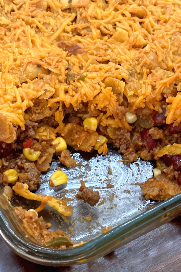 Chili cheese casserole in baking dish with one scoop taken out. 