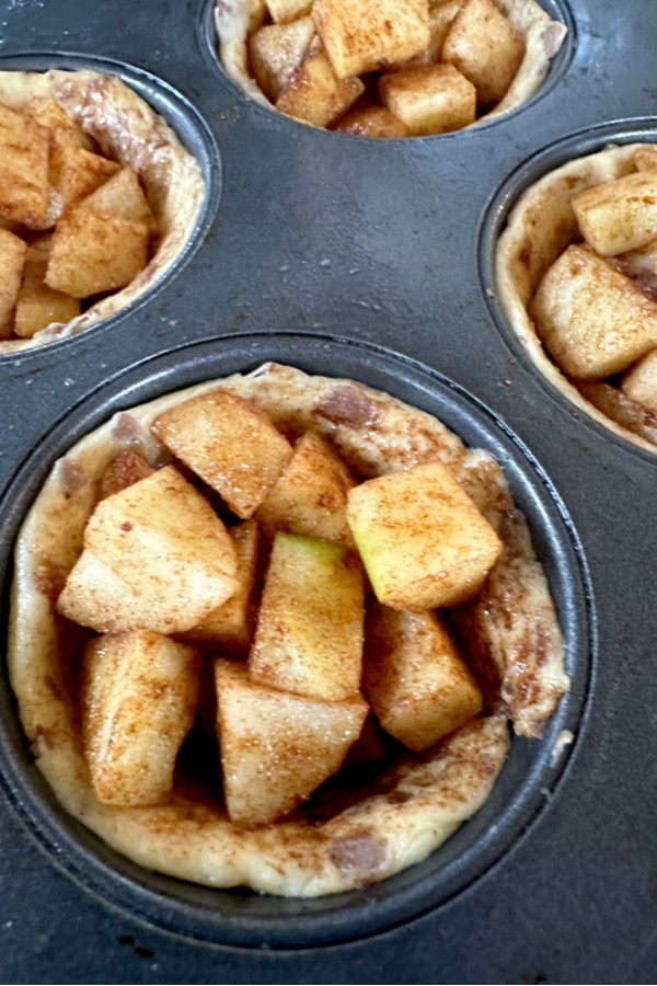 cinnamon rolls, topped with diced apples, ready to be put in the oven