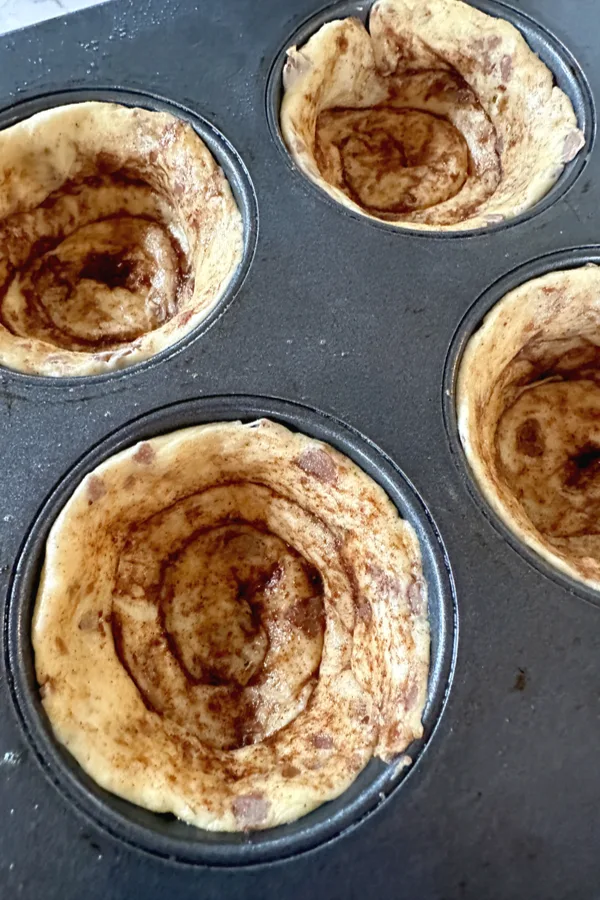cinnamon rolls in a muffin tin before being cooked.