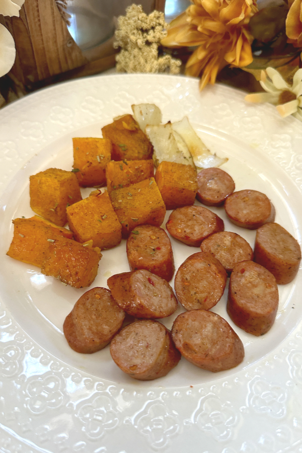 a dinner plate with sheet pan sausage and sweet potatoes.