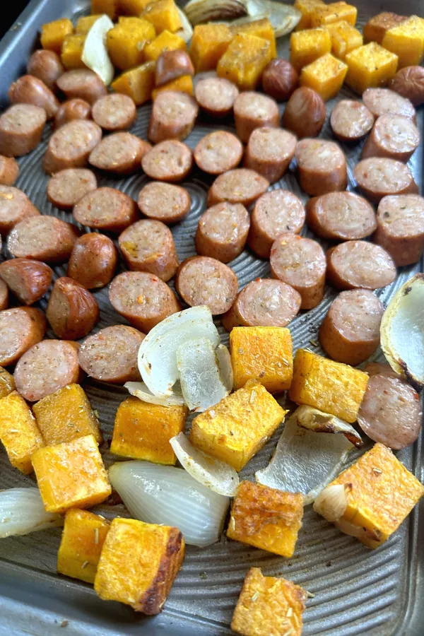 sheet pan sausage and sweet potatoes with sliced onions.