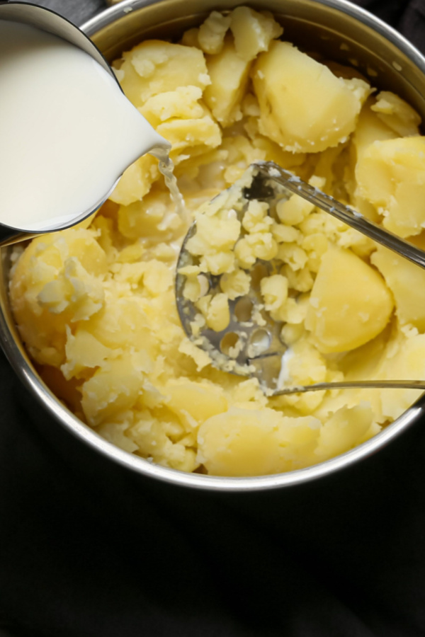 adding milk while mashing potatoes