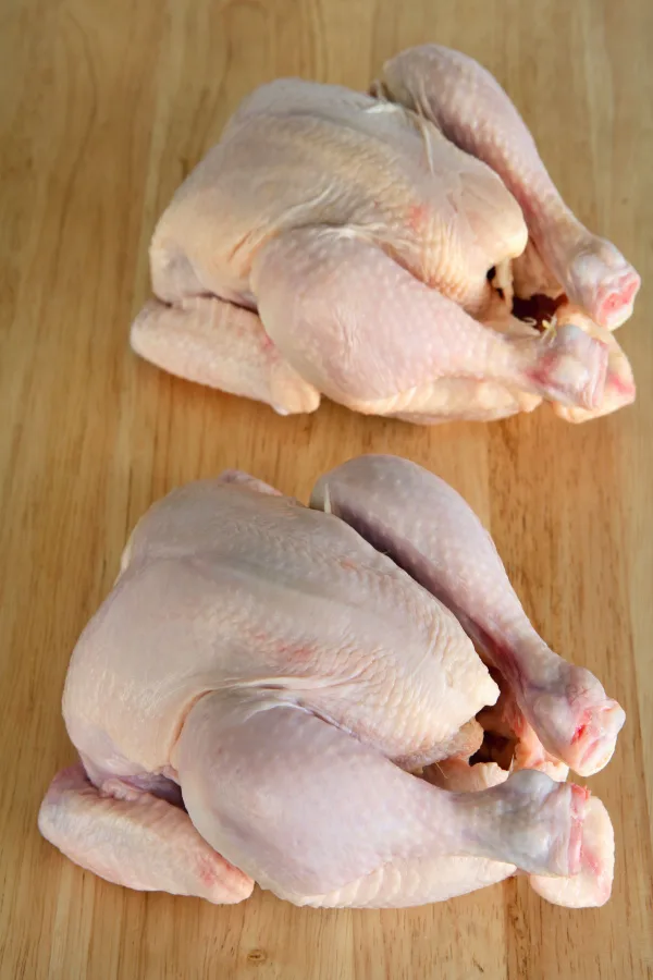 Two roasting chickens on a cutting board and ready to be prepared.
