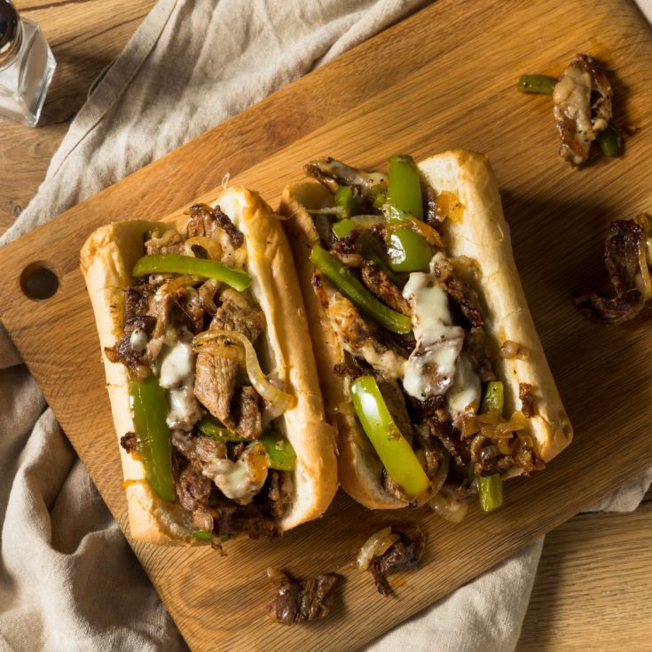 Philly cheesesteak hoagies on cutting board