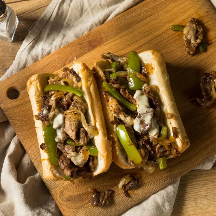Philly cheesesteak hoagies on cutting board